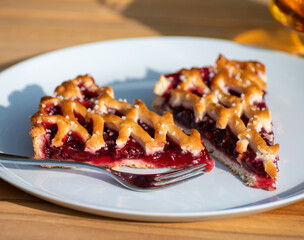 Homemade open sour cherry pie, delicious sweet dessert served in pieces outdoor in garden