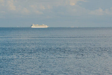 View south east towards Tampa Bay from Point Pinellas at Bay Vista Park. Large white cruise boat heading left to right and Blue sky with white clouds over calm blue water on a sunny day. 
