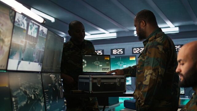 Air force officer performing tactical level surveillance in command room using laptop. Close up of military specialist in base of operations using radar on notebook to look at assault zones, camera B