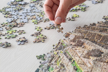 Macro photo of a male hand holding a piece of a jigsaw puzzle