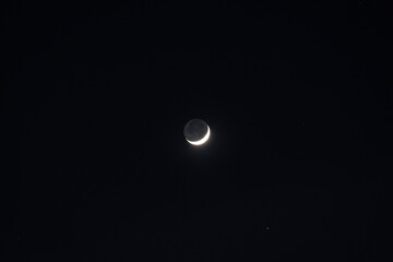 Beautiful waning crescent moon with stars in black night with no clouds