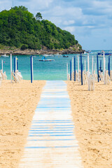 Pasarela hacia la playa con barcas al fondo