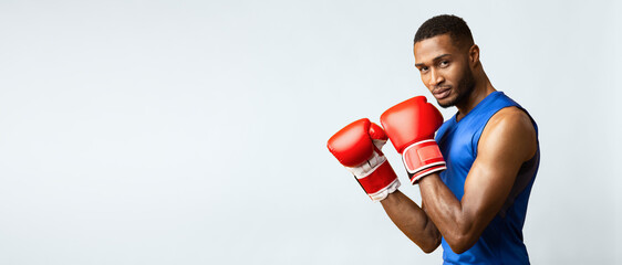 Fighter. Athletic black man in boxing stance looking at camera, yellow studio background. Side...