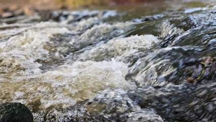 closeup of rolling water small waves in river stream nature background
