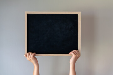 Child holding a small blackboard isolated on grey background