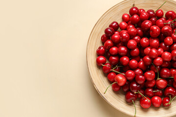 Plate with sweet cherries on beige background