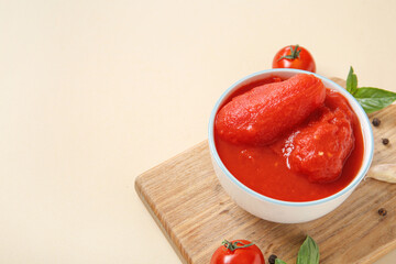 Wooden board with canned tomatoes and spices on color background
