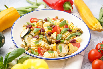Bowl of tasty pasta salad with tomatoes and basil on white background