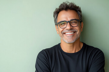 Middle-aged Brazilian man with glasses, friendly and confident smile, standing against a soft light green background, radiating warmth and positivity.