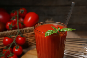 Glass of tasty tomato juice on wooden background