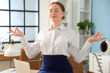 Young businesswoman meditating in office