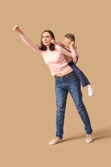 Beautiful mother with her cute little daughter having fun together on brown background