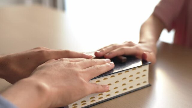 Hand on holy bible with cross as taking pledge loyalty for devotion, swearing and oath for truthful reliable at court as oathing a witness process. Catholic faith follower with bible. Burgeoning