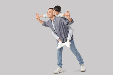 Fototapeta premium Cute little boy with his father on light background