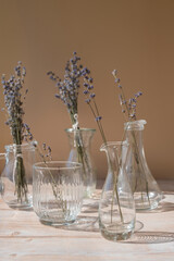 Dried lavender flowers in glass vase on neutral beige background. Minimal still life eco concept. Minimalistic interior decor with lavender flowers. Earth tones sustainability 