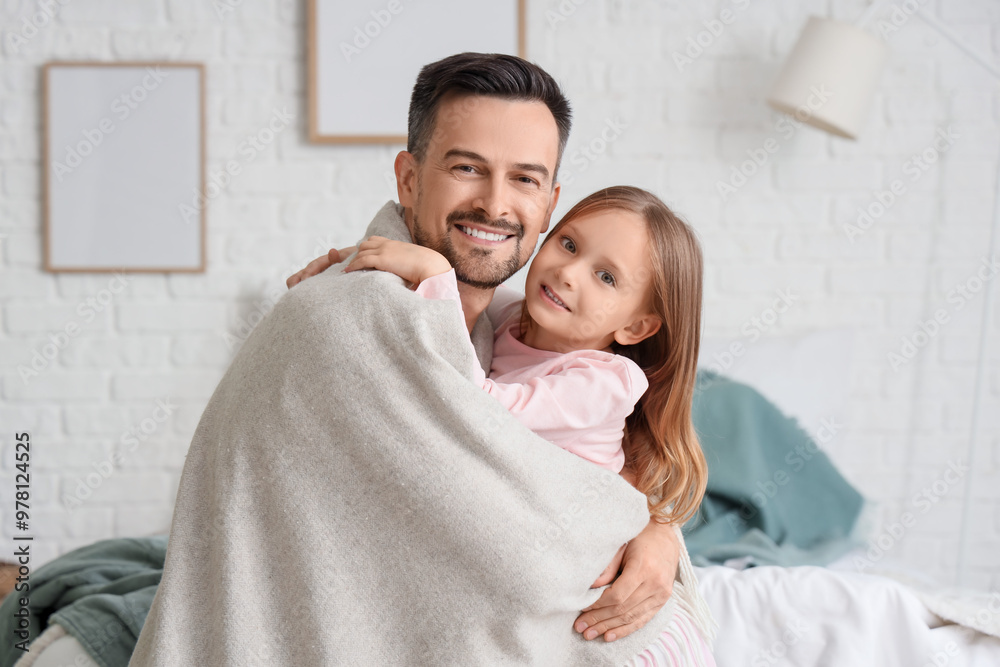 Wall mural Cute little girl and her father with warm plaid hugging in bedroom