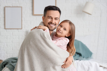 Cute little girl and her father with warm plaid hugging in bedroom