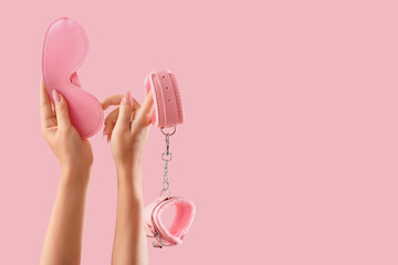 Woman with mask and handcuffs from sex shop on pink background