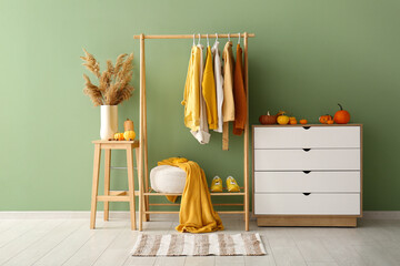 Fototapeta premium Interior of hallway with autumn clothes, drawers and pumpkins