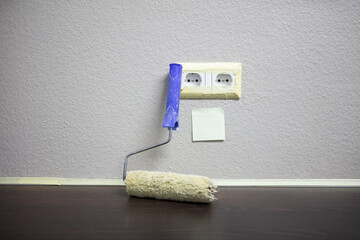 A smooth, newly painted wall featuring an empty sticky note and a cleaned paint roller. Finished work, minimalist composition. 
