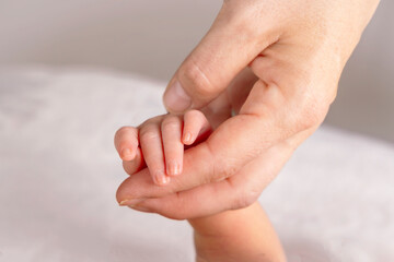 Image of a close up of an infant's hand held by a mother's hand wearing a wedding ring.