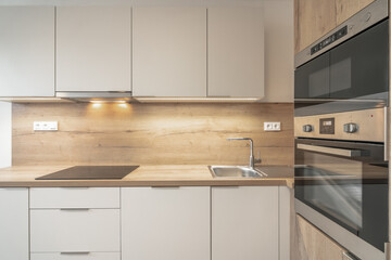 A modern kitchen with wooden countertops, cabinets, an oven, microwave, sink, and stovetop. The...