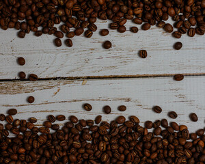 Gran cantidad de Granos de cafe  moka tostado sobre un fondo de madera blanca con relieve