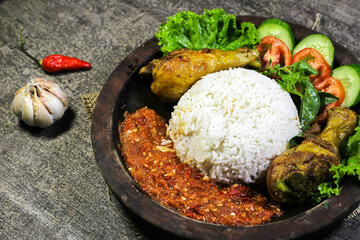 Ayam penyet (smashed fried chicken) is Indonesian East Javanese cuisine, served with sambal chili, lettuce and cucumber slice