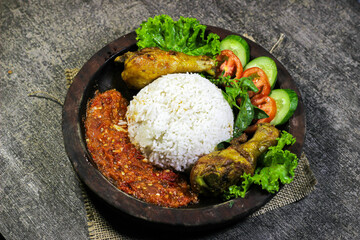 Ayam penyet (smashed fried chicken) is Indonesian East Javanese cuisine, served with sambal chili, lettuce and cucumber slice