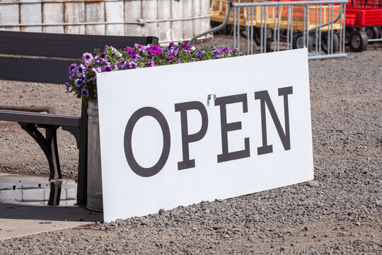 "Opem" sign in a upick farm, where people can pick organic fruits and vegetables by themselves. Big Open sign on a white board in front of pink violet flowers