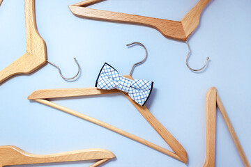 Wooden hanger with a checkered bow tie surrounded by other clothes hangers. Men's clothing sale concept. Selective focus