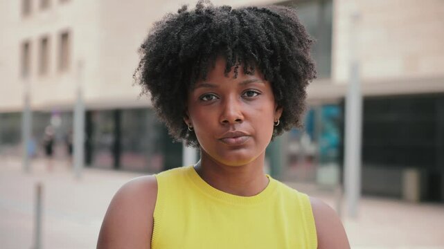 Close up individual portrait of one serious teenage african american girl looking at camera outside. A pensive young adult woman staring front . Proud afro female gazing with thoughtfull expression