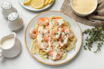 Tasty pasta with shrimps, creamy sauce and cheese served on white table, flat lay
