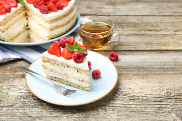 Tasty sponge cake with fresh berries and mint served on wooden table, space for text