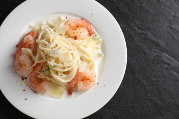 Delicious pasta with shrimps and cheese on black table, top view