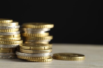 Stacked coins on wooden table against black background, closeup with space for text. Salary concept