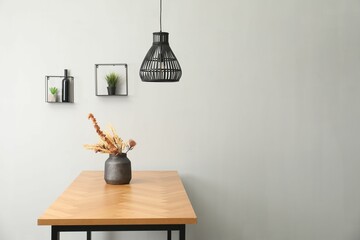 Vase with bouquet of dried flowers on wooden table indoors. Space for text