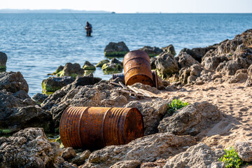 Fototapeta premium The environmental problem is rusty barrels on the seashore.