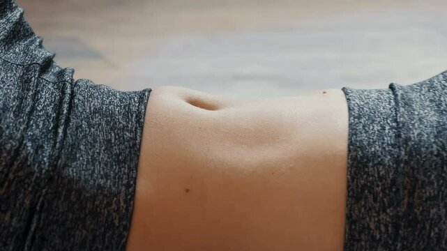 A person is practicing yoga in a peaceful studio, showcasing a close-up of their abdominal area. The individual is focused on maintaining balance and mindfulness during their routine.