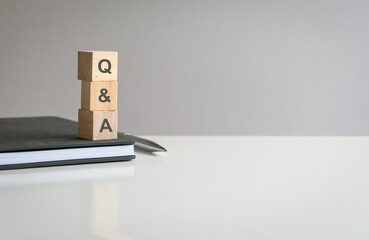 Text Q&A on wooden blocks on top of a notepad of a white color table. Copy space.