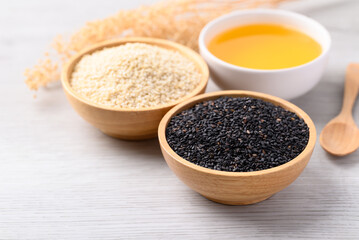 Black and white sesame seeds and oil (Cold pressed) in bowl on white table, Food ingredient