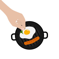 Female hand puts greens on a fried egg in a frying pan with sausage and spices. Isolated on white