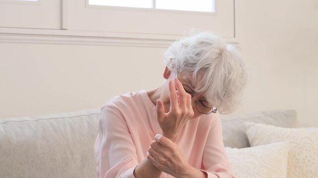 手が痺れるシニア女性　リビングルーム