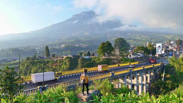 Young man looking at the view of Sigandur bridge and the mountain in the background.