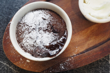 Delicious Chocolate Lava Cake with Powdered Sugar and Whipped Cream on Wooden Plate