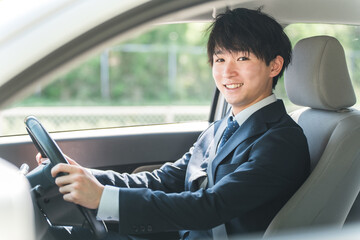 車を運転するスーツ姿の若い男性ビジネスマン
