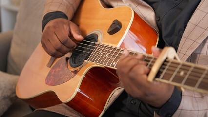 Guitar musician. Talented performer. Creative hobby. Inspired man hands playing blues song melody on string acoustic instrument on couch at home.