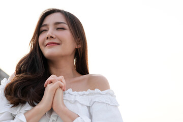 Asian woman smiling with eyes closed feeling peaceful and serene, relaxing outdoor in natural sunlight, enjoying the moment, positive thinking concept, self-love and wellness, fresh air breathing