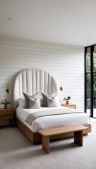 minimalist bedroom with a clean and serene aesthetic. The room features a large bed with a unique, curved headboard upholstered in a light, textured fabric