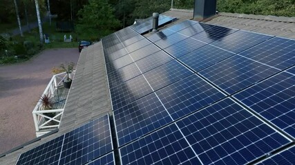 Drone flying backwards over reflecting solar panels on a house roof, autumn day